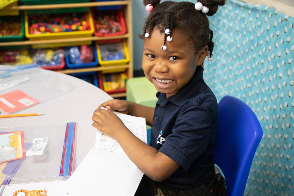 student at tuition-free charter school Palm Beach Maritime Academy smiling while seated at a classroom table